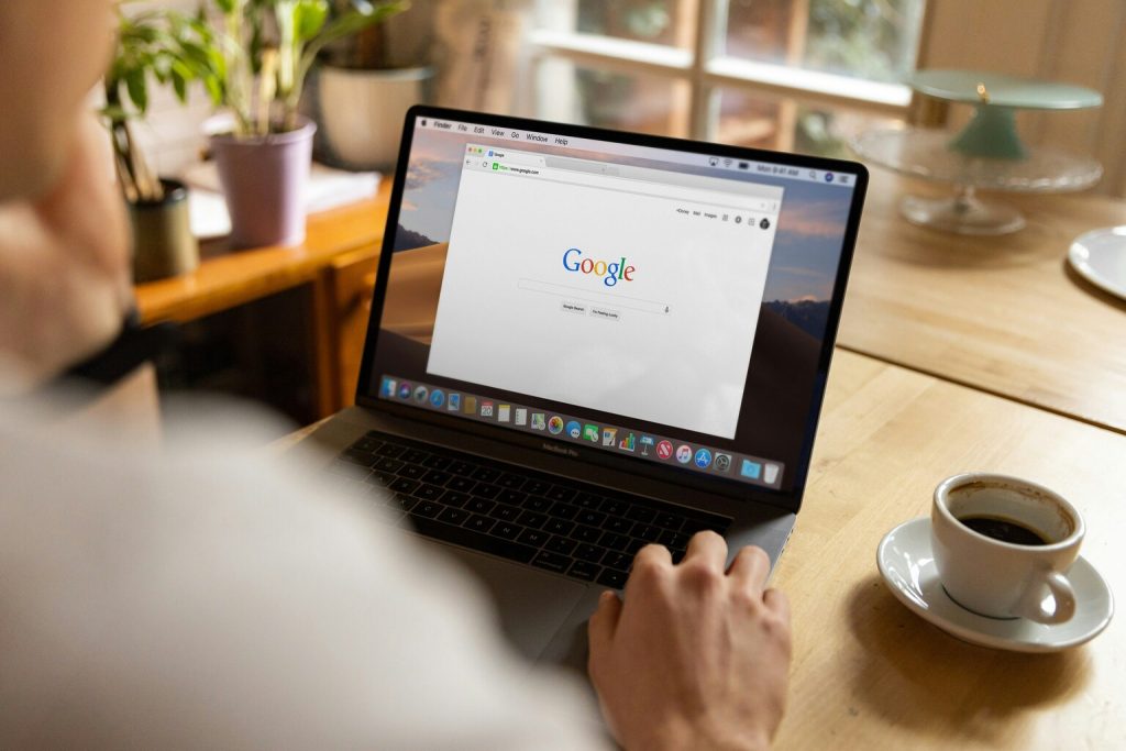 Person using macbook pro on table, searching google website.